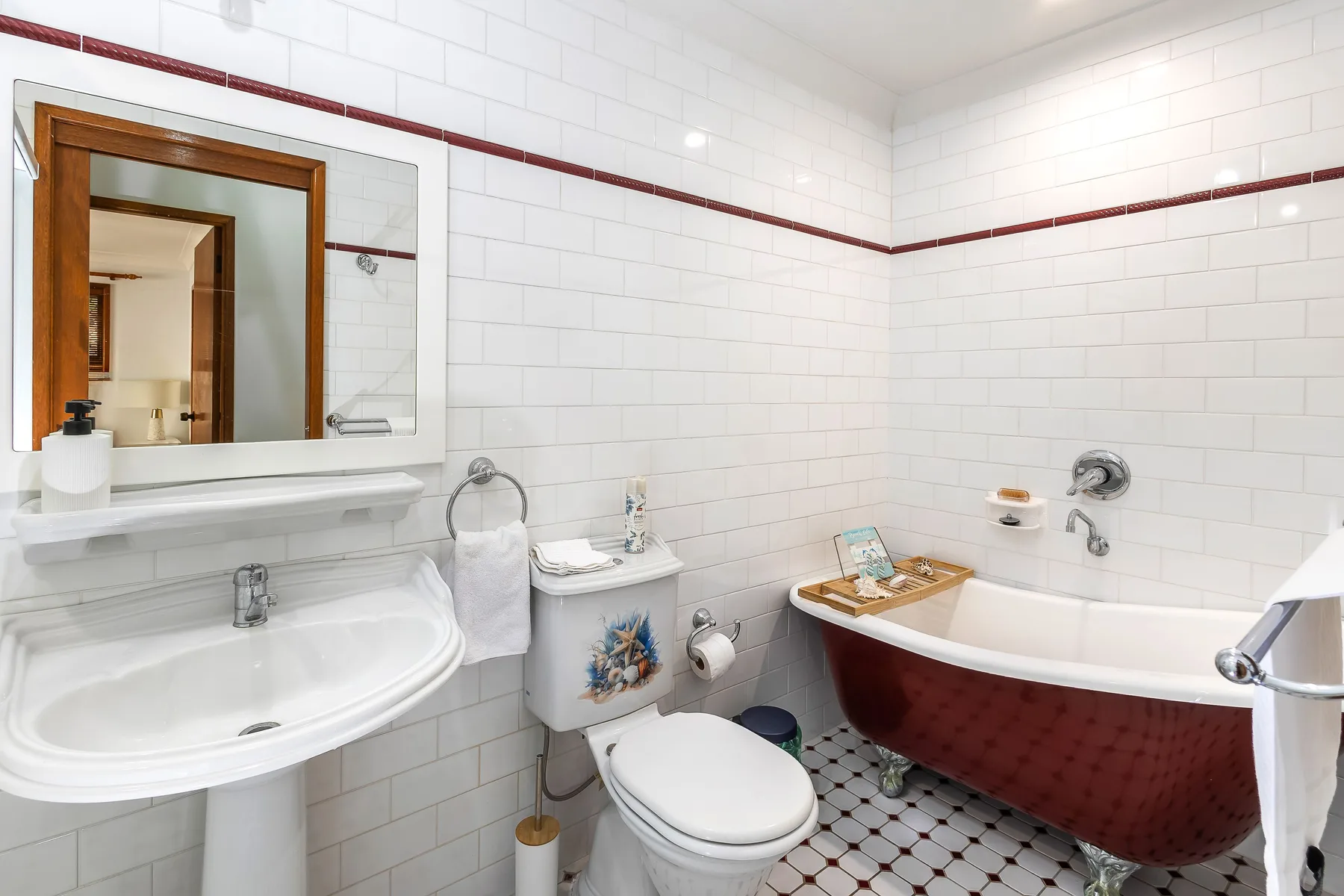 Baño con azulejos, lavabo, inodoro y bañera.