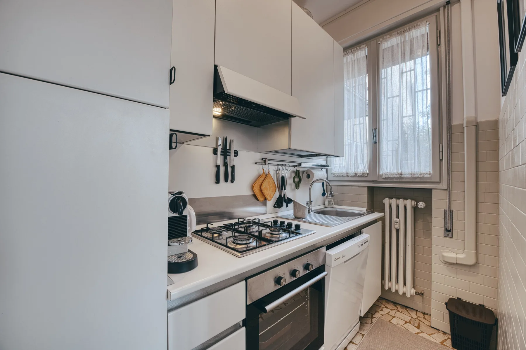 Una cocina compacta con estufa y fregadero debajo de una ventana.