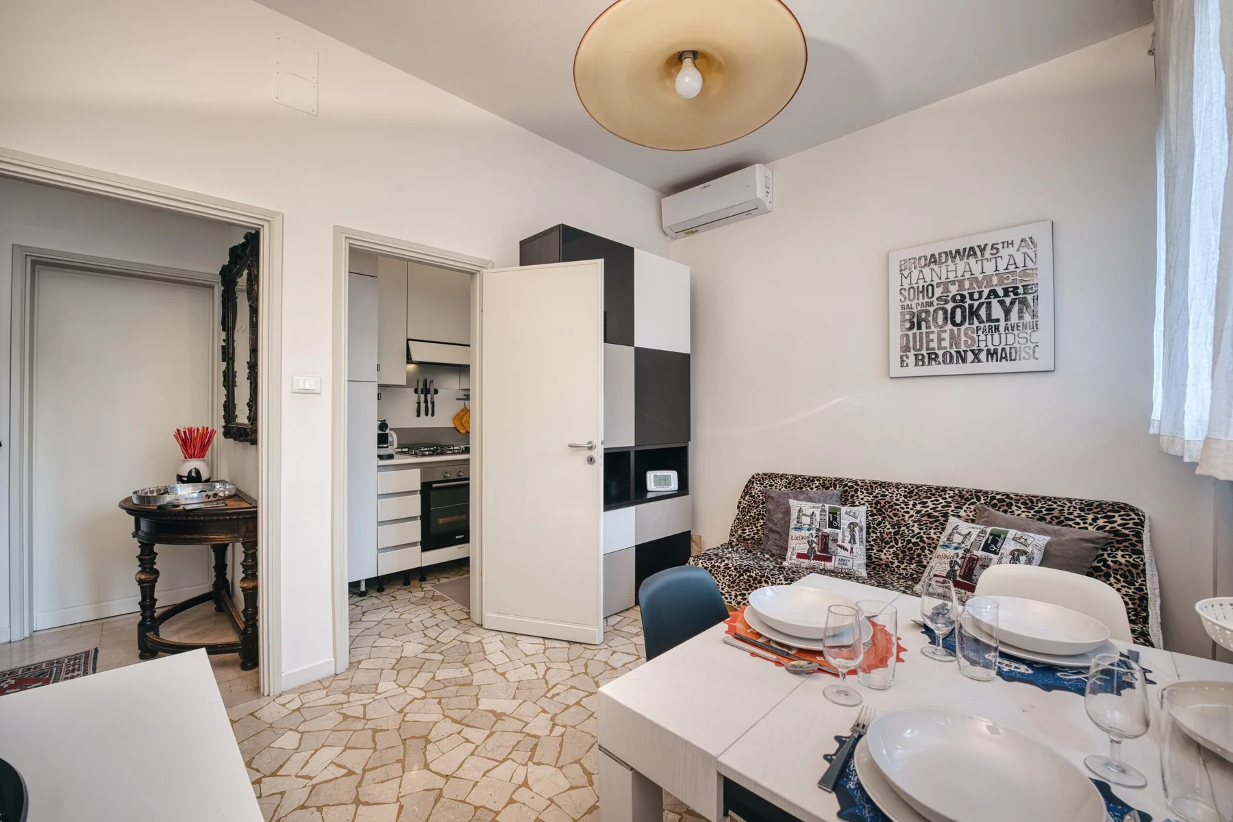 Comedor con la mesa puesta, asientos estampados y una entrada abierta a la cocina.