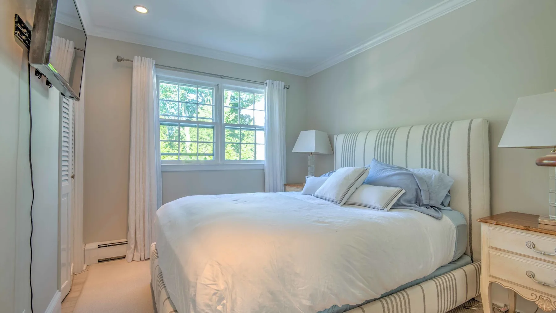 A bedroom with a large bed, striped headboard, and a window.
