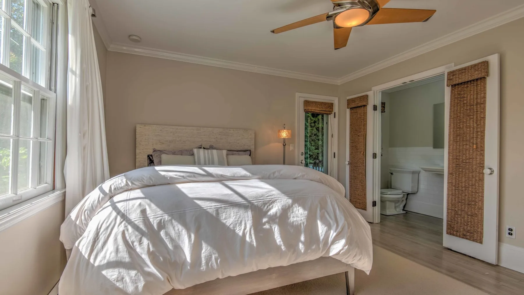 A bright bedroom with a large bed and an open doorway to a bathroom.