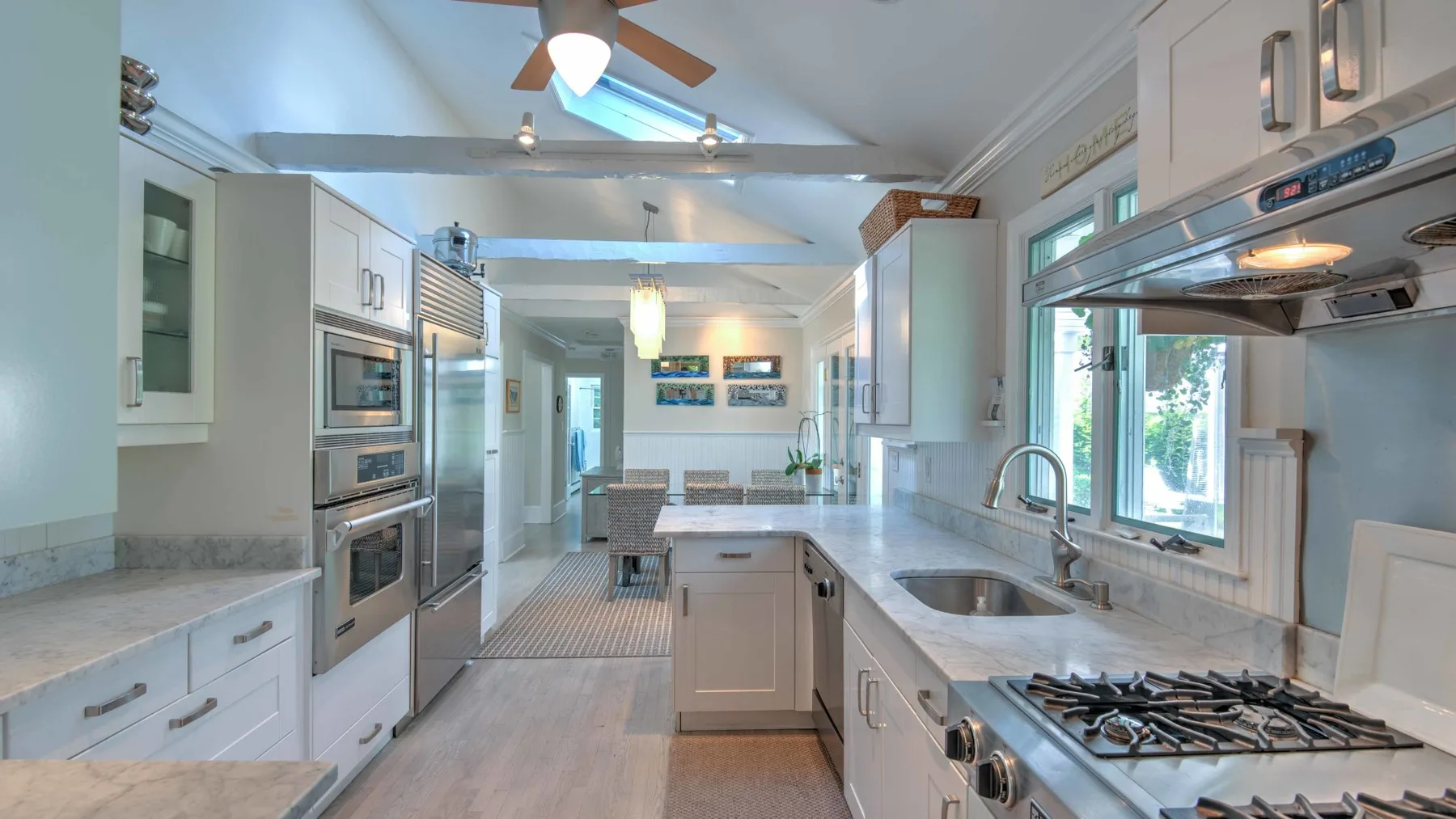 A bright kitchen with a central island, built-in appliances, and windows.