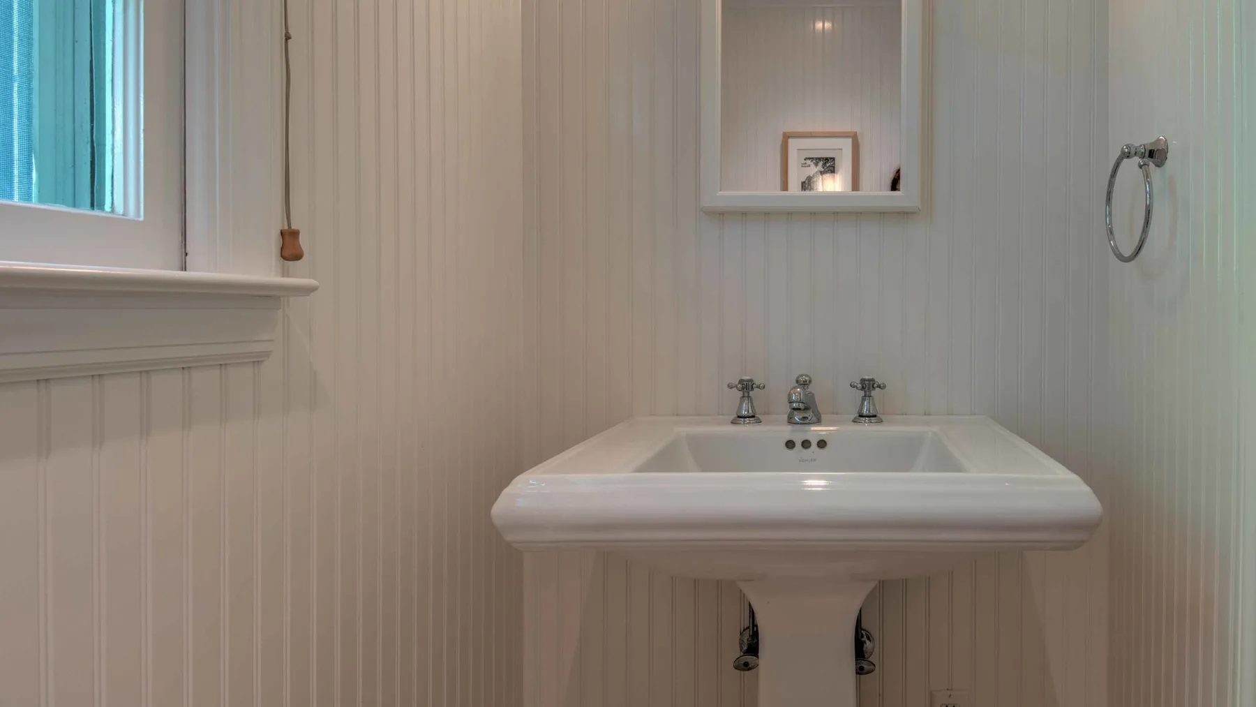 A bathroom with a wide white sink beneath a wall mirror.