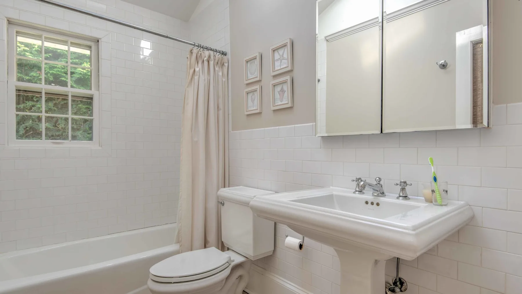 A bright bathroom with a bathtub, sink, and window.