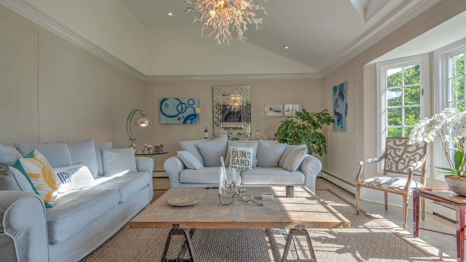 A bright living room with light-colored seating and large windows.