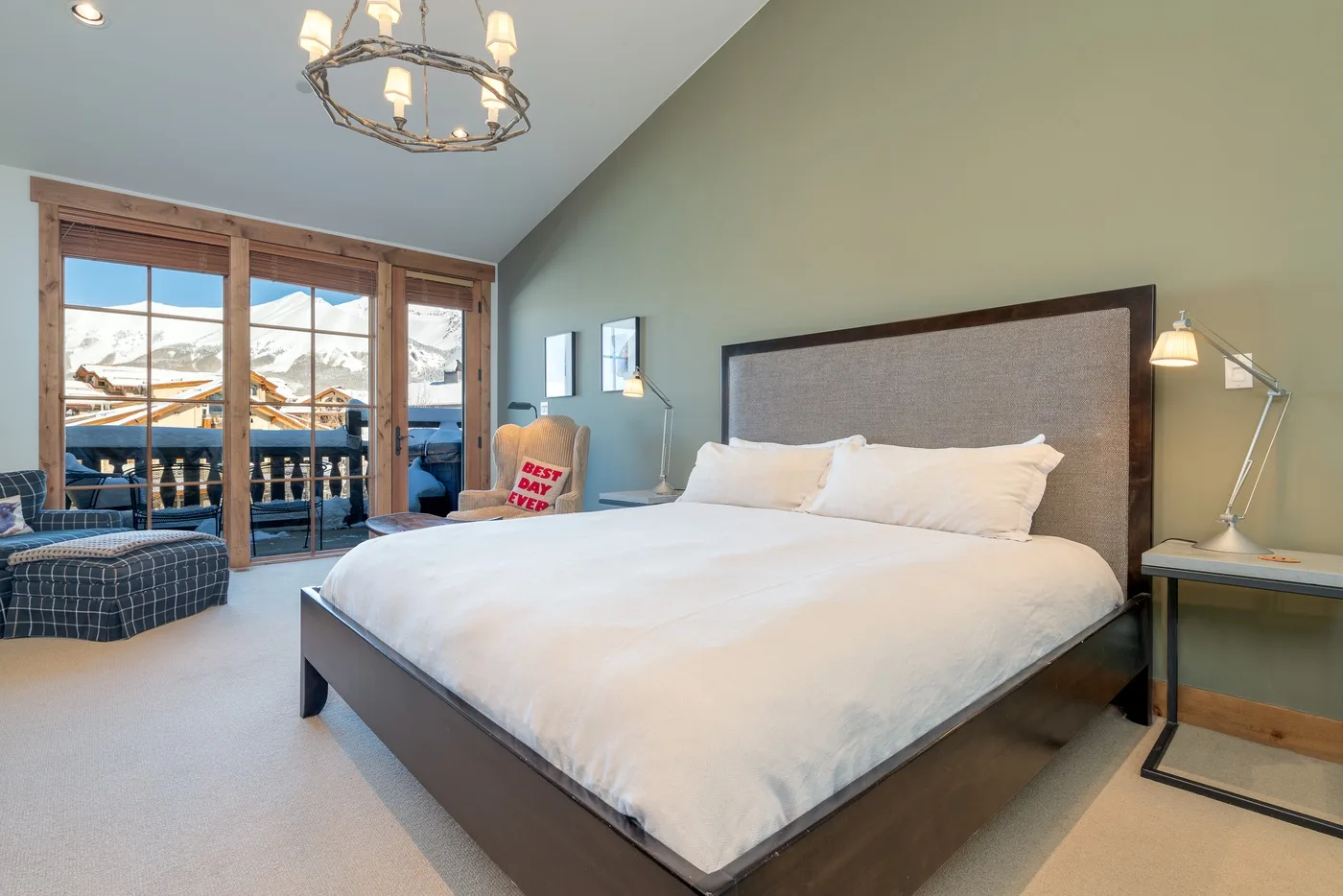 A bedroom with a large bed beside glass doors overlooking a mountain view.