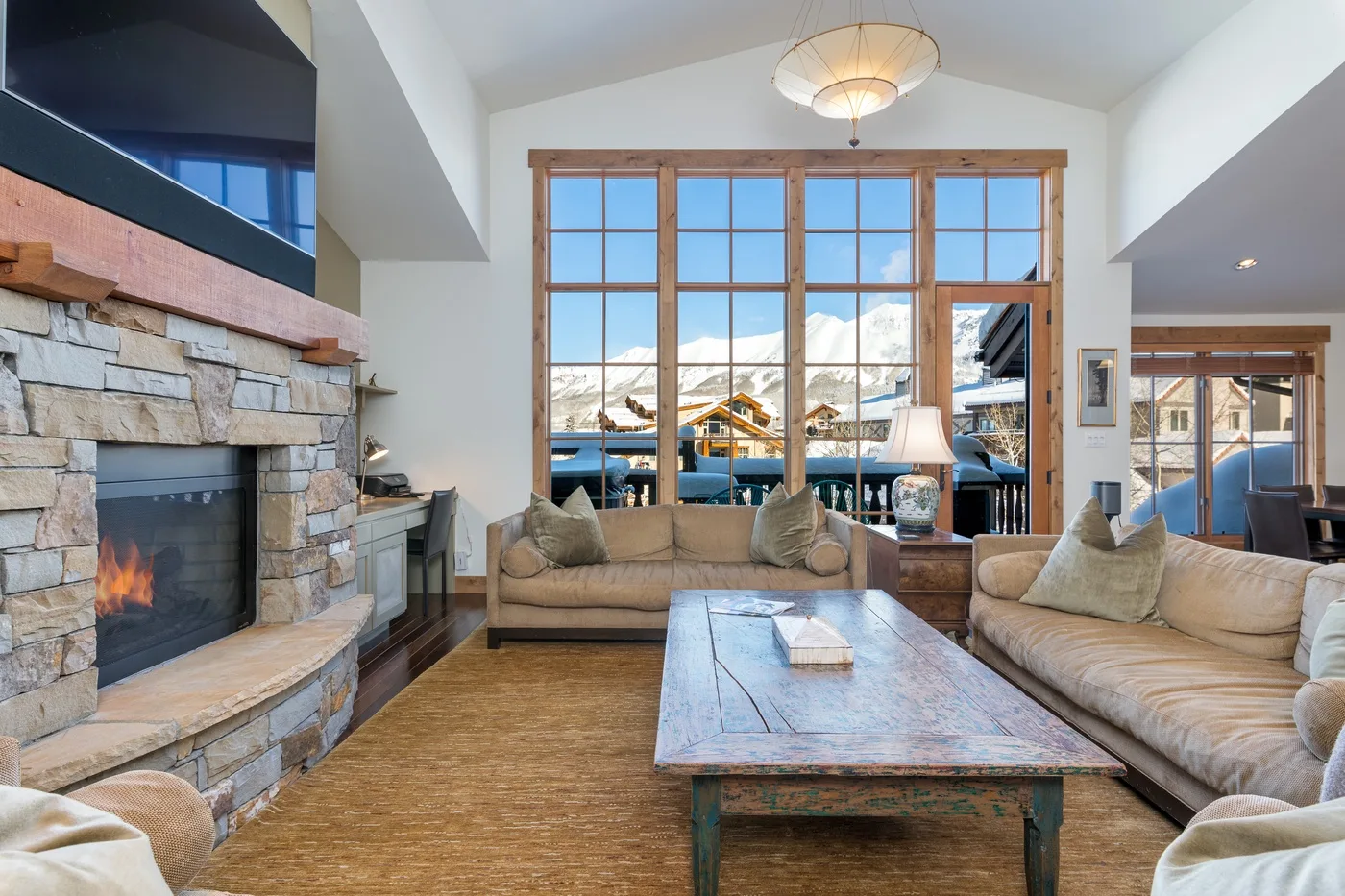 A living room with seating around a coffee table and a stone fireplace.