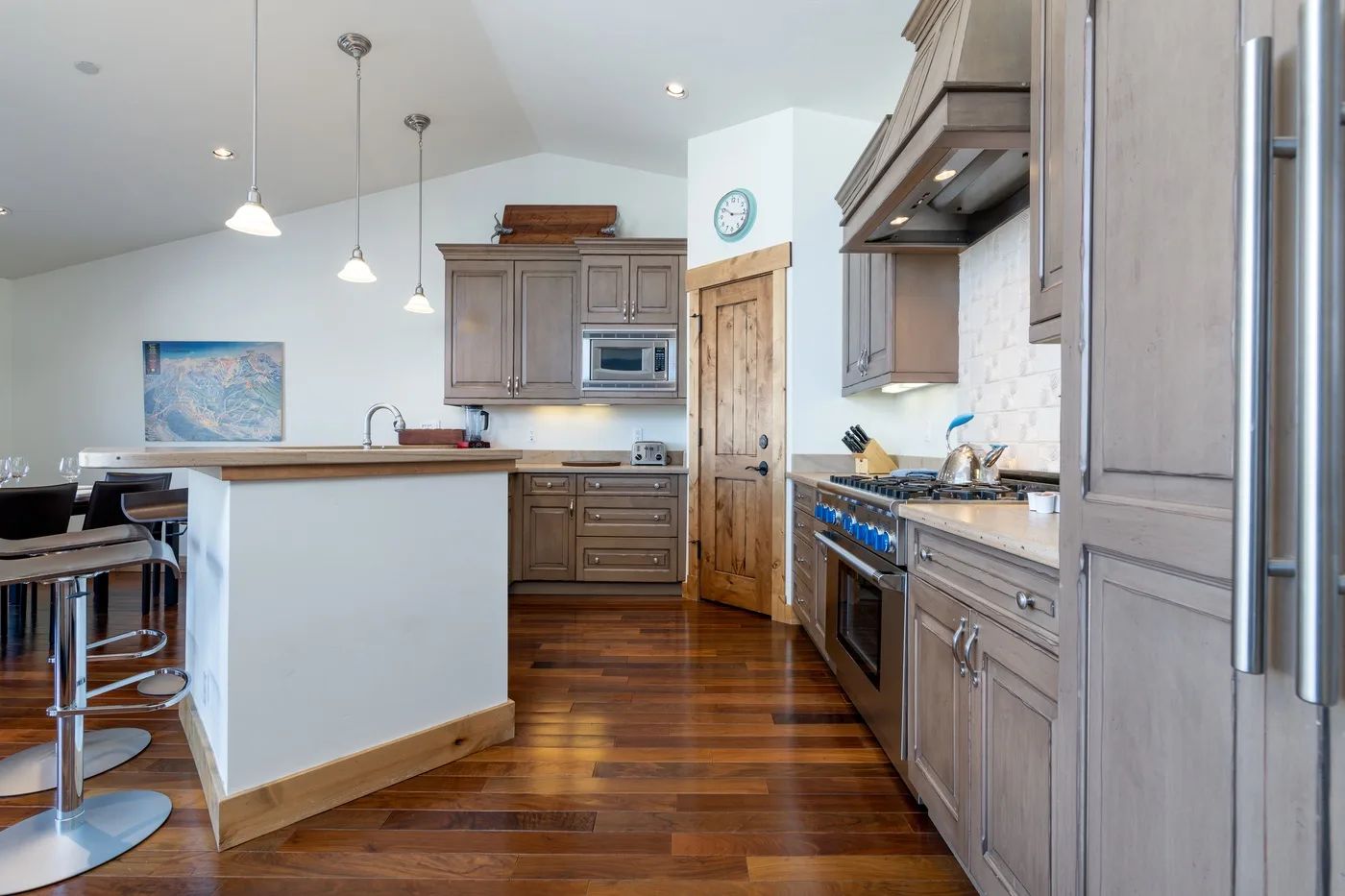 A kitchen with gray cabinetry, a central island, and stainless steel appliances.
