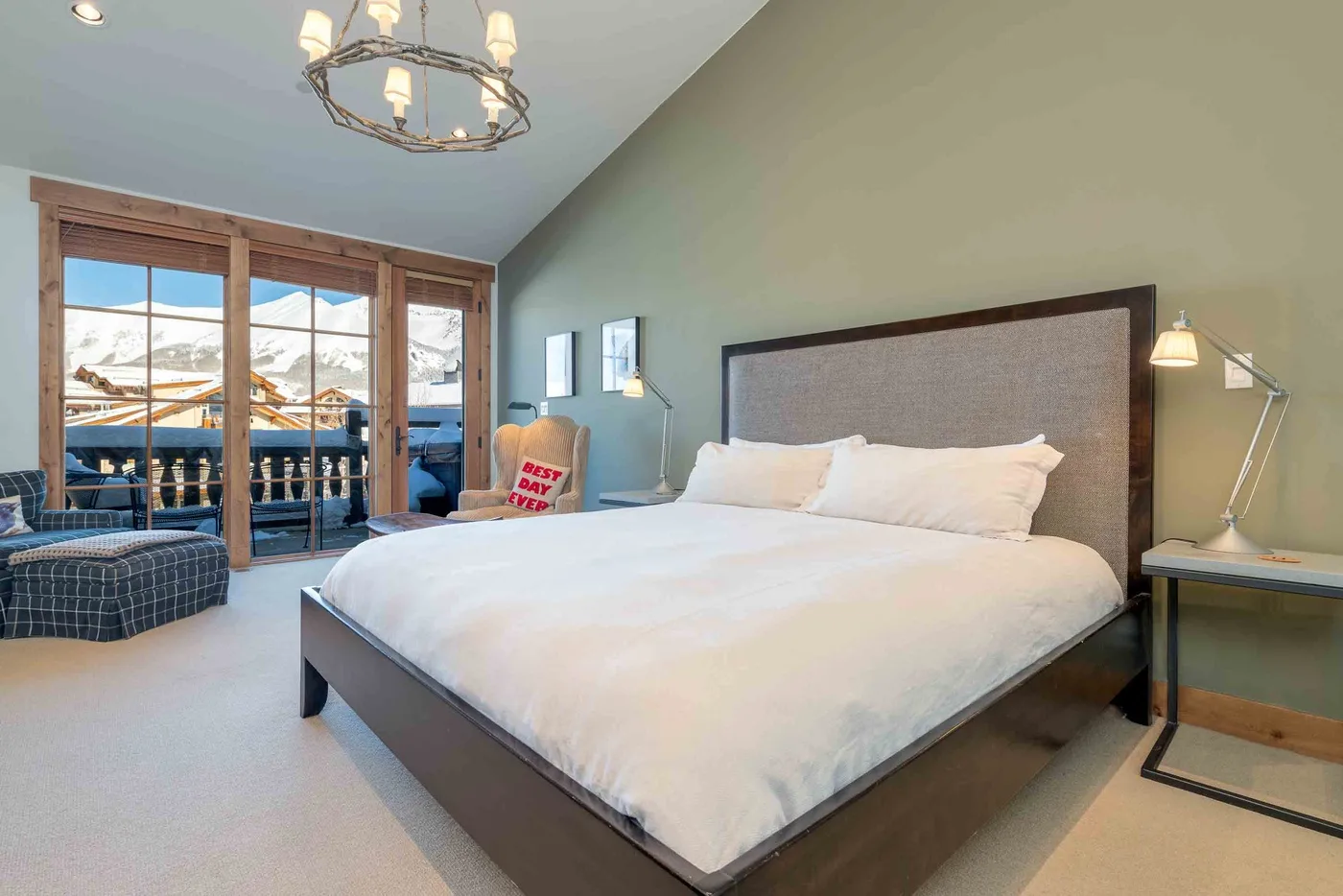 A bedroom with a large bed and glass doors overlooking a snowy landscape.