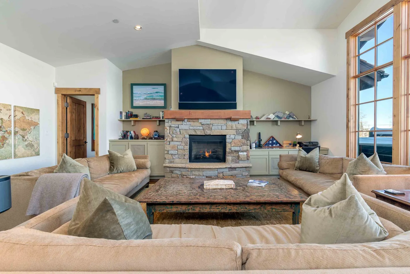 A living room with seating arranged around a stone fireplace and television.