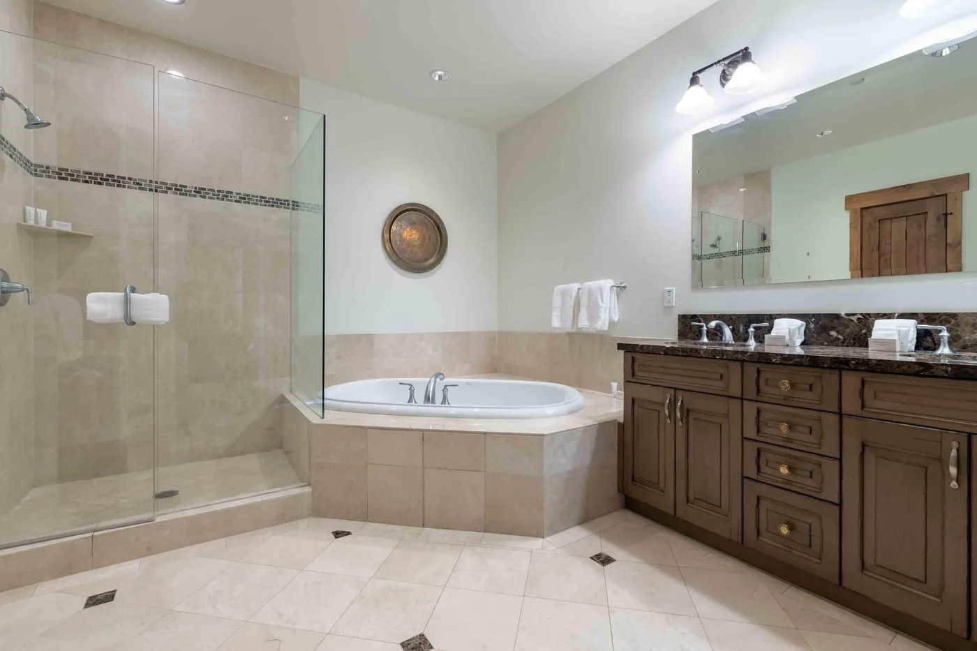 A spacious bathroom with a glass shower, soaking tub, and wooden vanity.