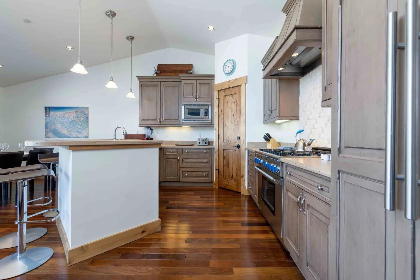 A spacious kitchen with a central island, wood cabinetry, and stainless steel appliances.