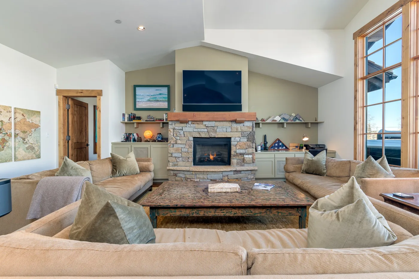 Living room with seating arranged around a stone fireplace and television.