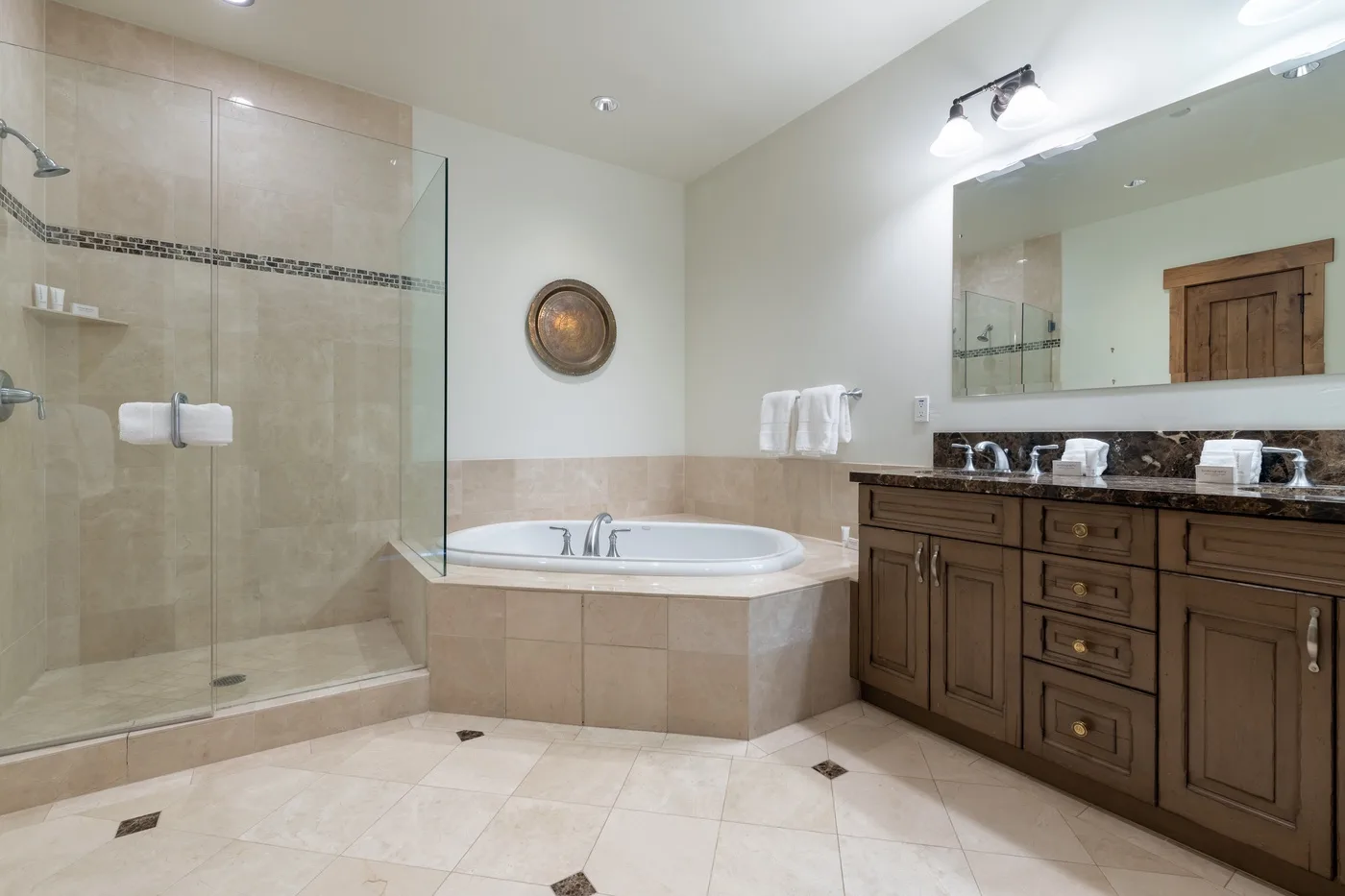 A spacious bathroom with a glass shower, a bathtub, and a long vanity.
