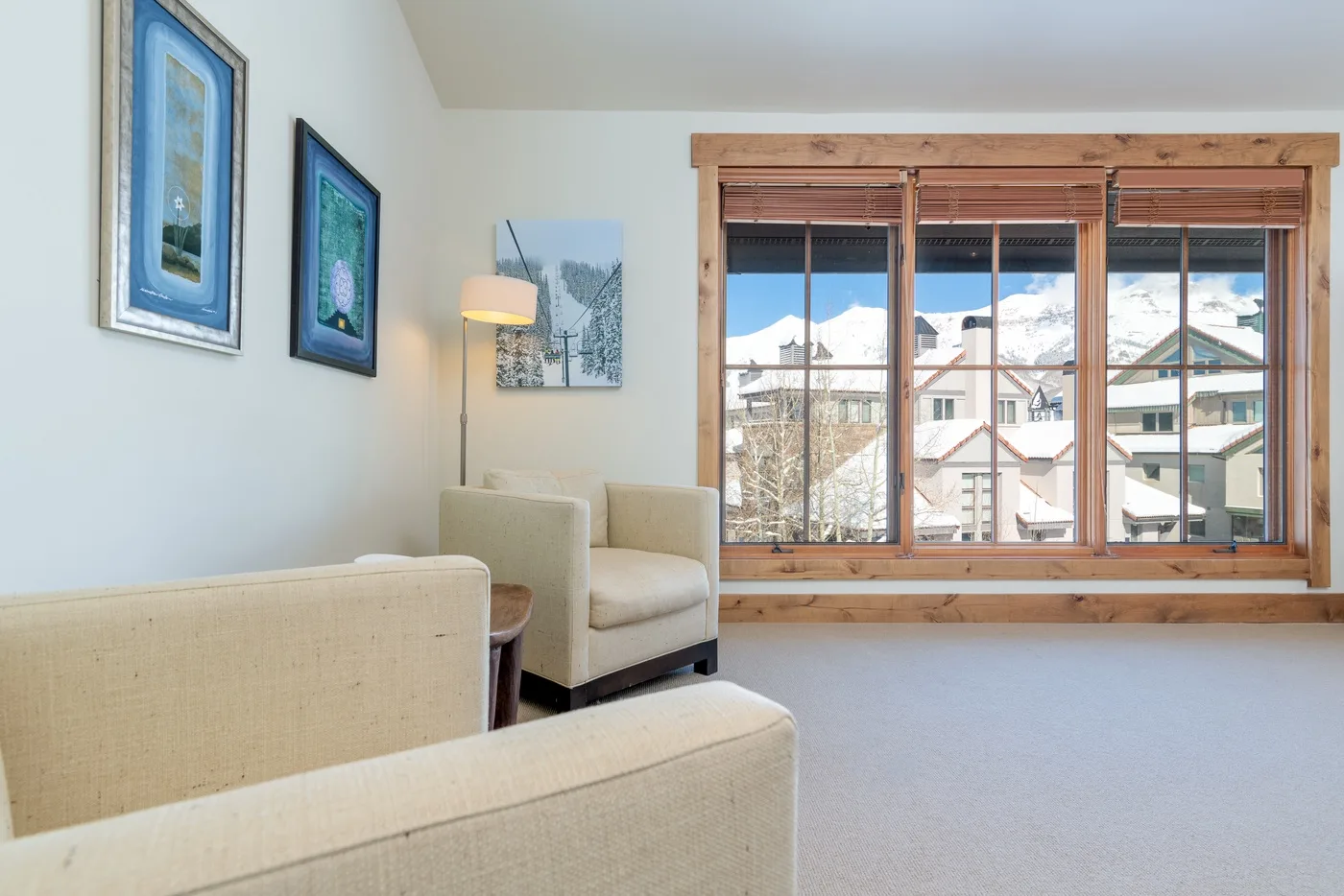 A bright living area with seating beside a large window overlooking nearby buildings.