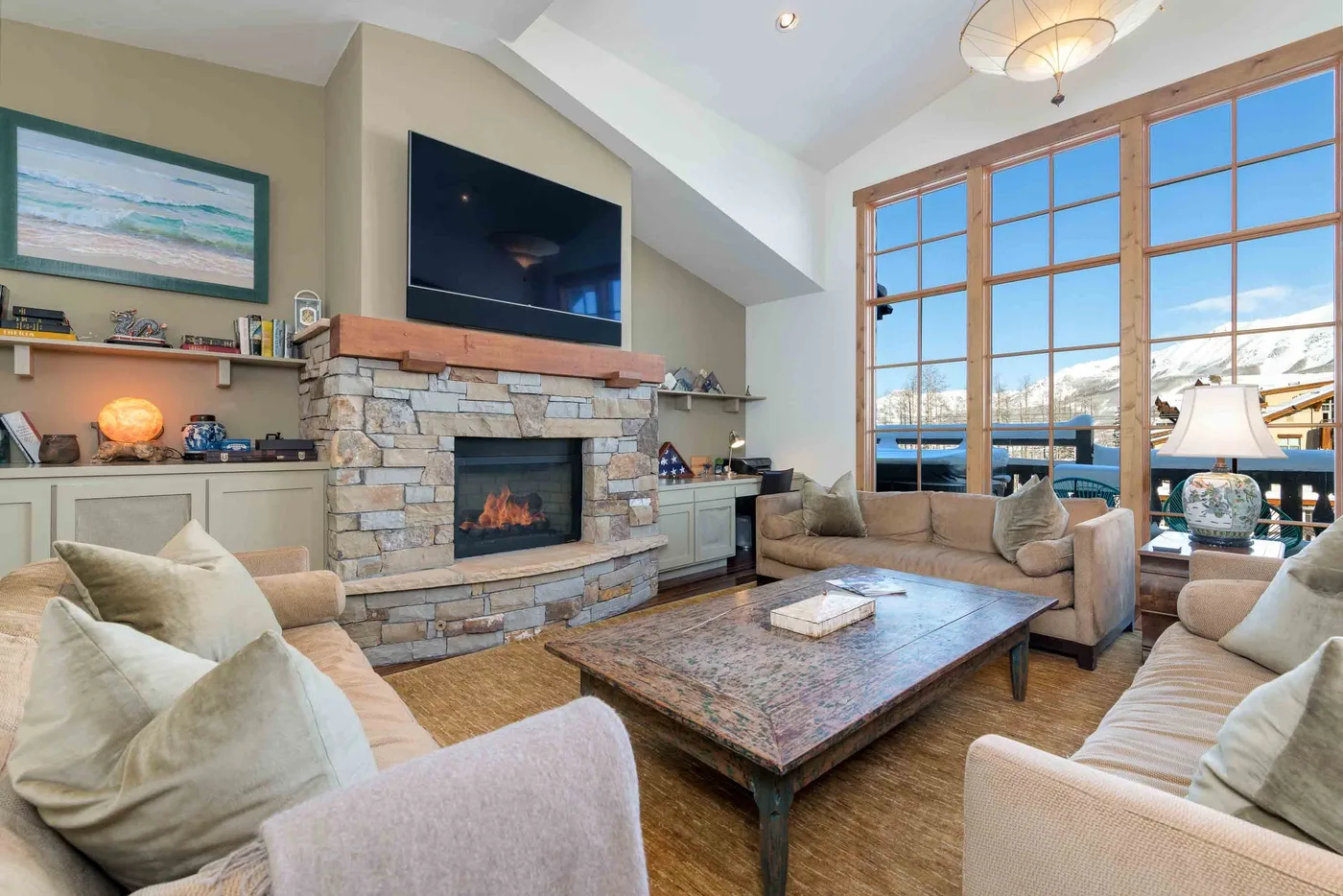A bright living room with seating around a coffee table and a stone fireplace.