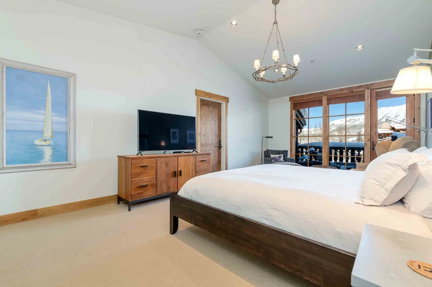 A bright bedroom with a large bed and glass doors overlooking the water.