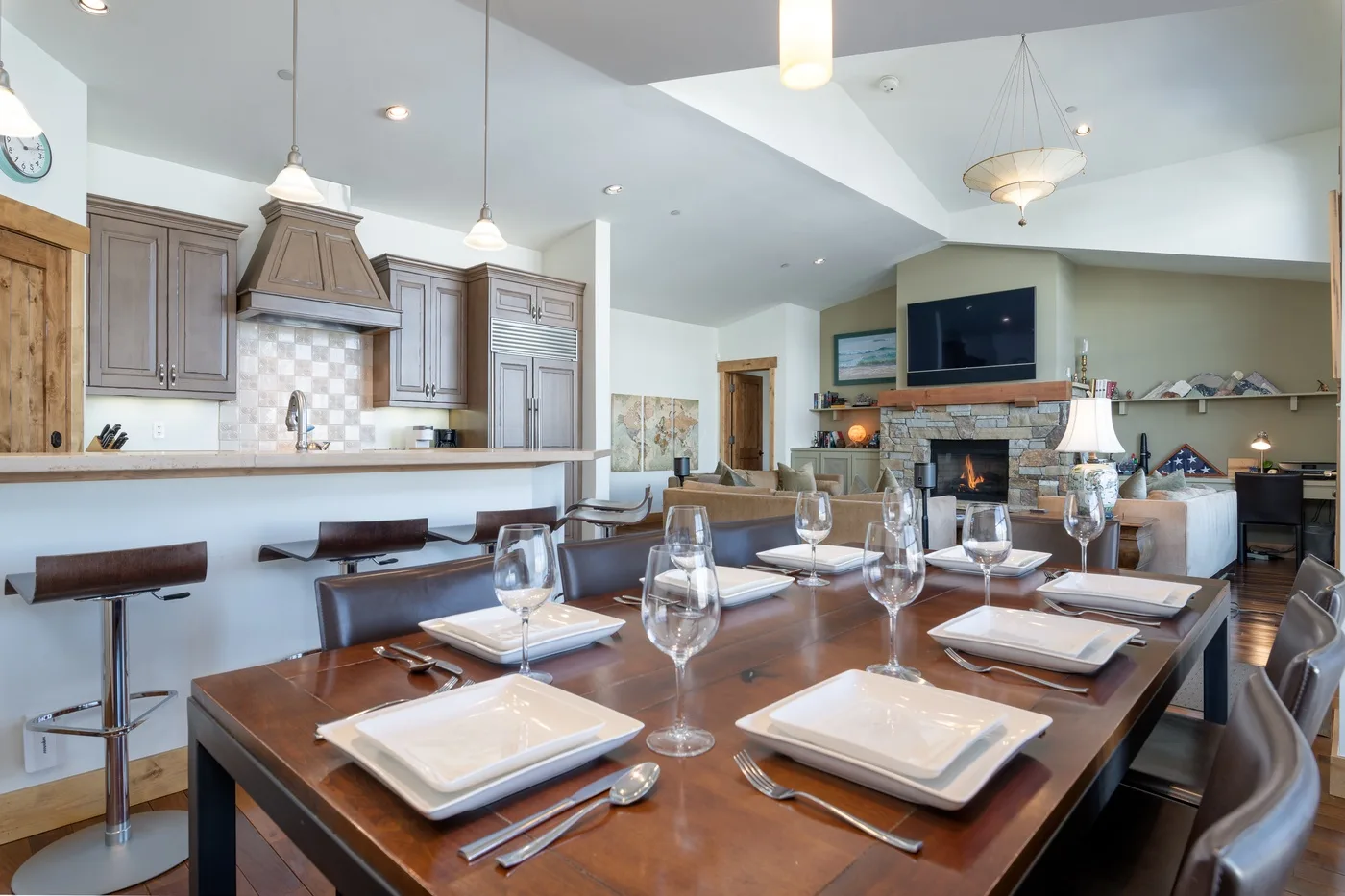 An open dining area with a set table beside a kitchen and living room.