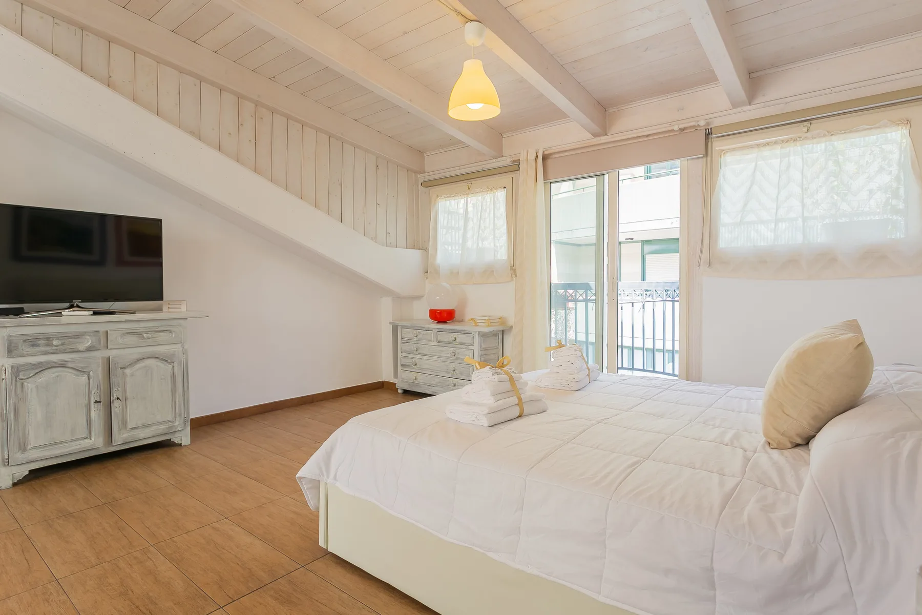 Un dormitorio luminoso con una cama grande y puertas de vidrio que dan a un balcón.