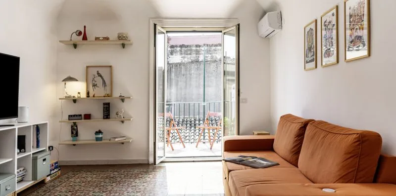Una sala de estar con asientos, un televisor y puertas de vidrio que dan a un balcón.