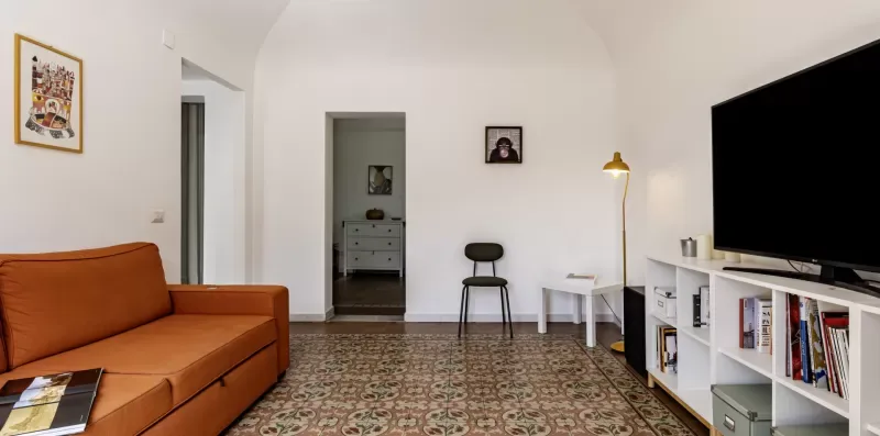 Una sala de estar con asientos naranjas, suelo estampado y un televisor.