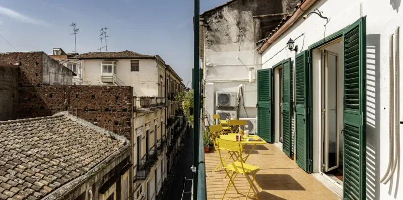 Una terraza estrecha con asientos amarillos junto a un edificio blanco.
