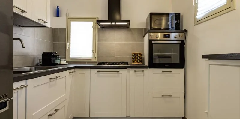Una cocina con gabinetes blancos, una encimera y electrodomésticos empotrados.