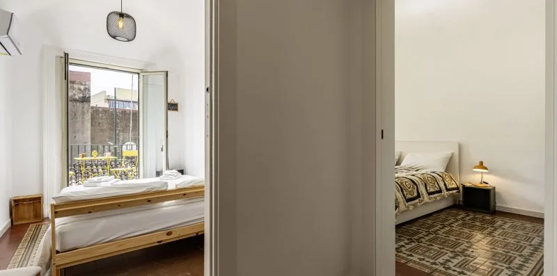 Un dormitorio con una cama junto a una ventana grande y una mesita de noche.