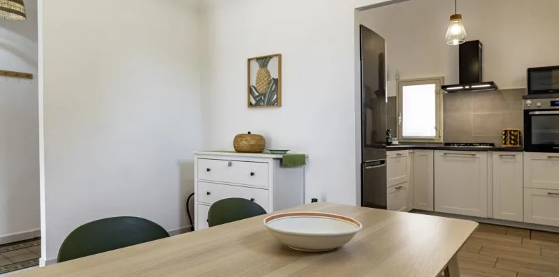 Una mesa de comedor con un cuenco está frente a una cocina.