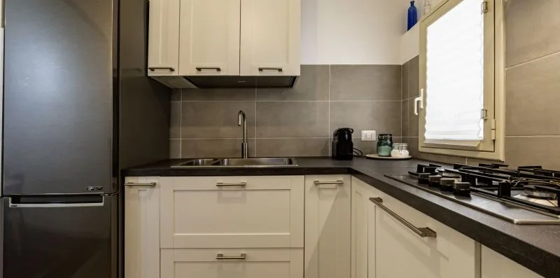 Una cocina compacta con gabinetes claros, encimeras oscuras y una ventana sobre la encimera.