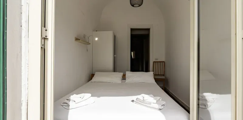 Un dormitorio con una cama tendida y una puerta al fondo.