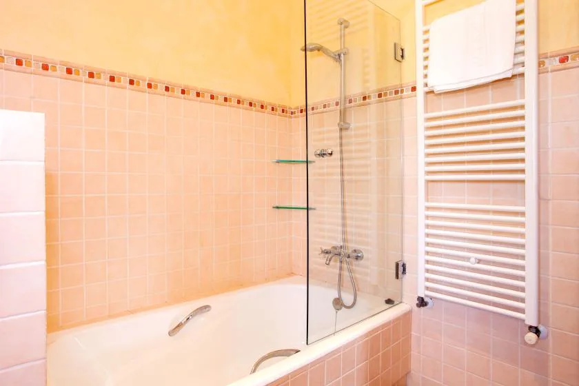 A tiled bathroom with a bathtub, shower, and towel warmer.