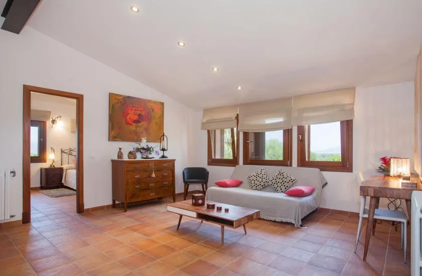 A bright living room has a sofa, wooden coffee table, and wide windows.