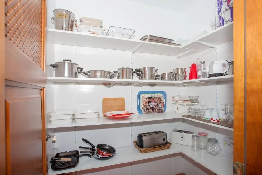 A tiled kitchen with open shelves holding cookware and dishes.