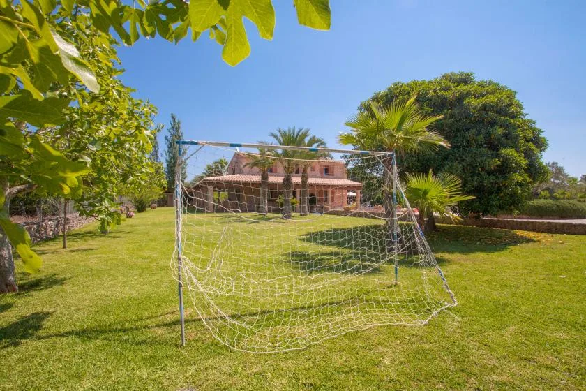A soccer goal stands on a green lawn in front of a brick building.