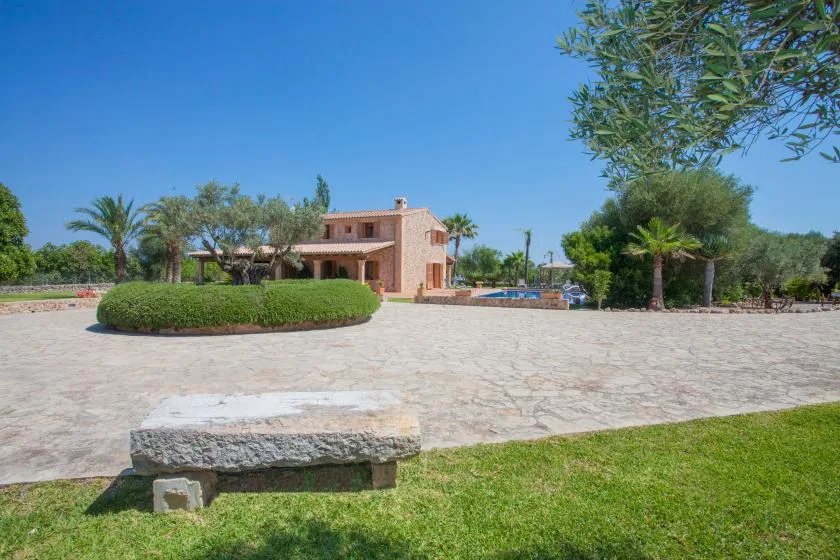A large paved courtyard surrounds a landscaped garden and a low building.