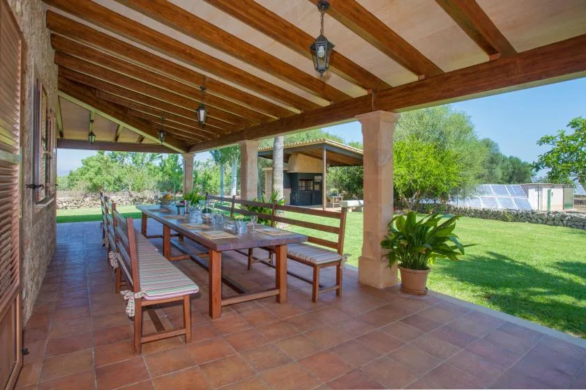 A covered outdoor dining area with a long wooden table and benches.