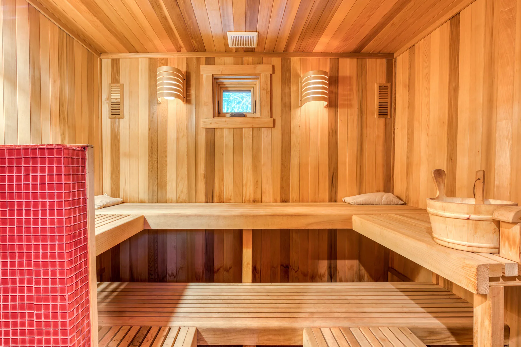 A wood-paneled sauna with tiered benches and a small window.