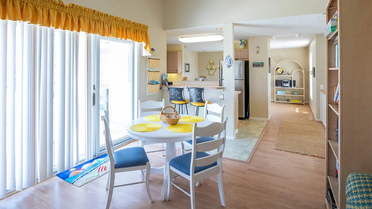 Un comedor luminoso junto a puertas corredizas de vidrio da a una cocina.
