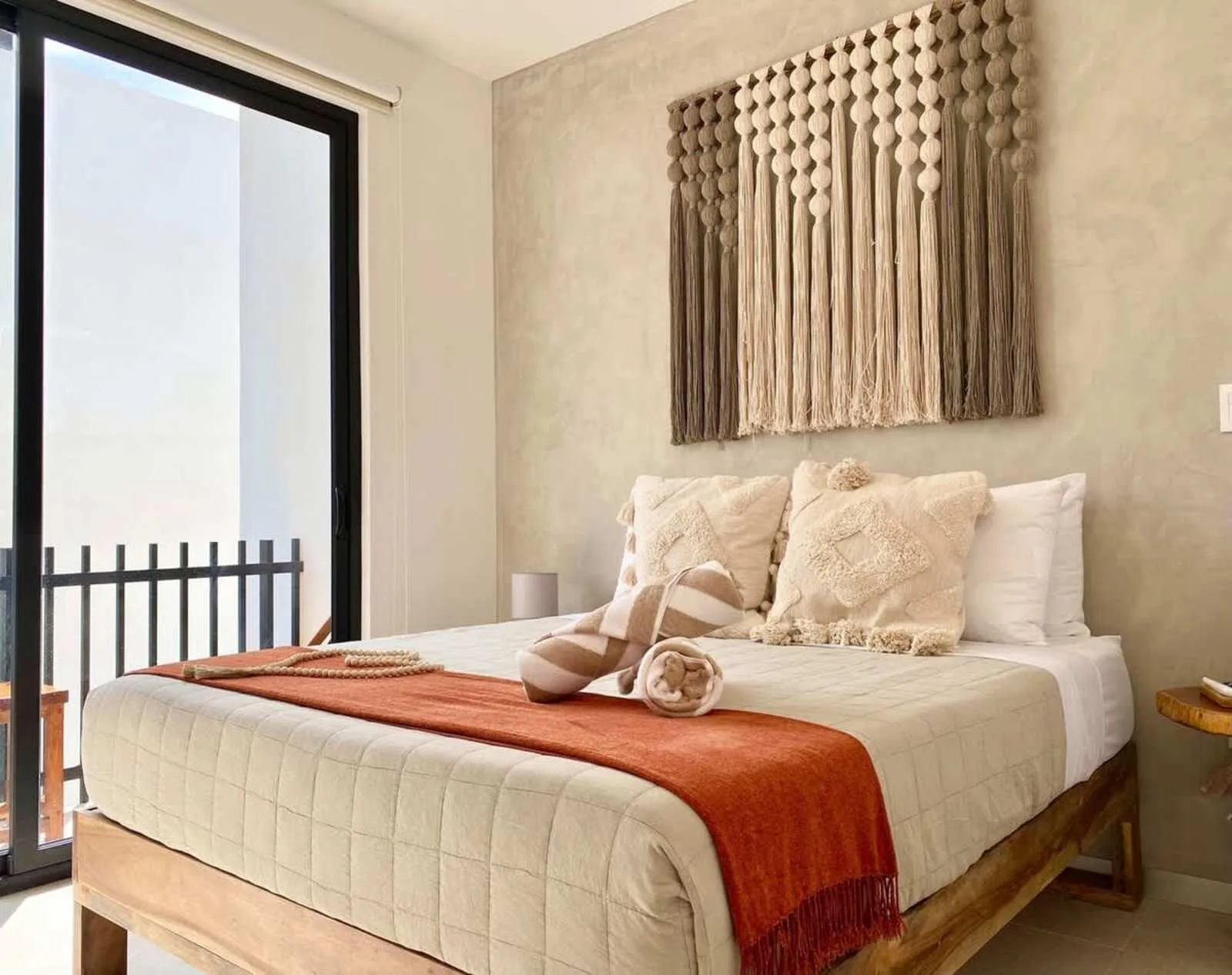 Un dormitorio con una cama bien tendida y un tapiz texturizado en la pared.