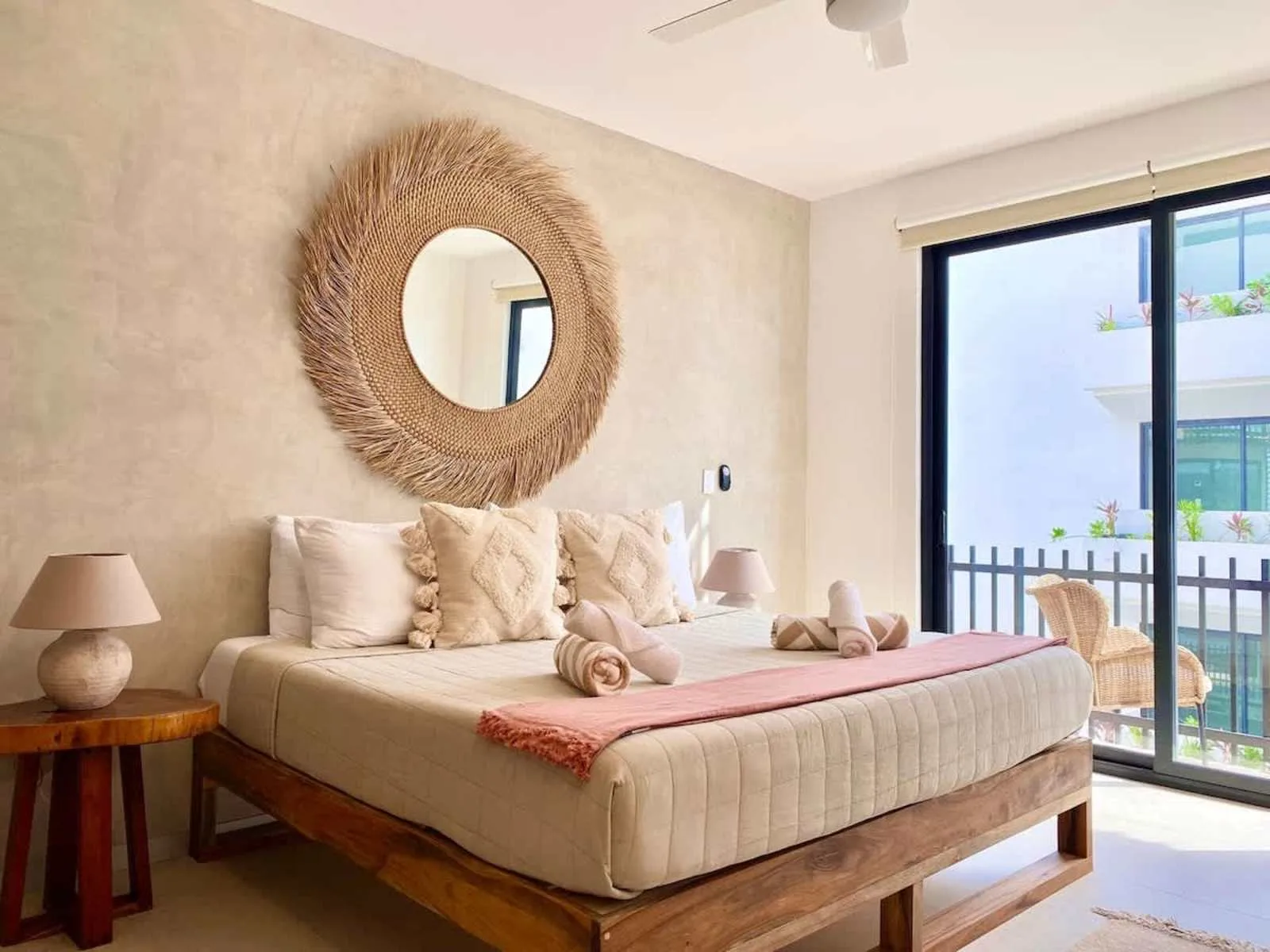 Un dormitorio con una cama grande, un espejo redondo y puertas corredizas de vidrio.