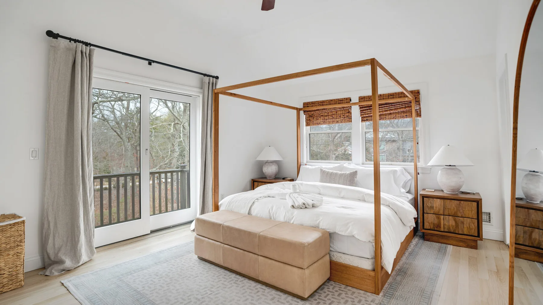 Un dormitorio luminoso con cama con dosel y puertas de vidrio que dan a un balcón.