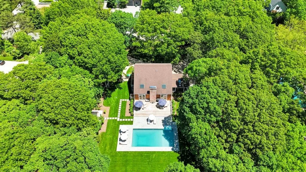 Vista aérea de una casa, una piscina y árboles alrededor.