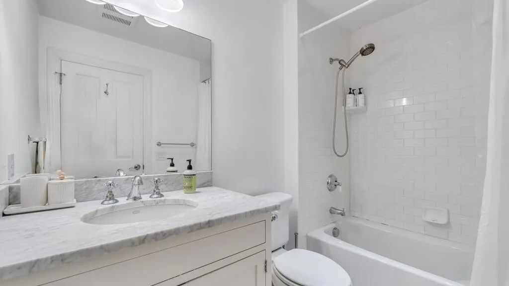 Un baño luminoso con un lavabo amplio, espejo y bañera.