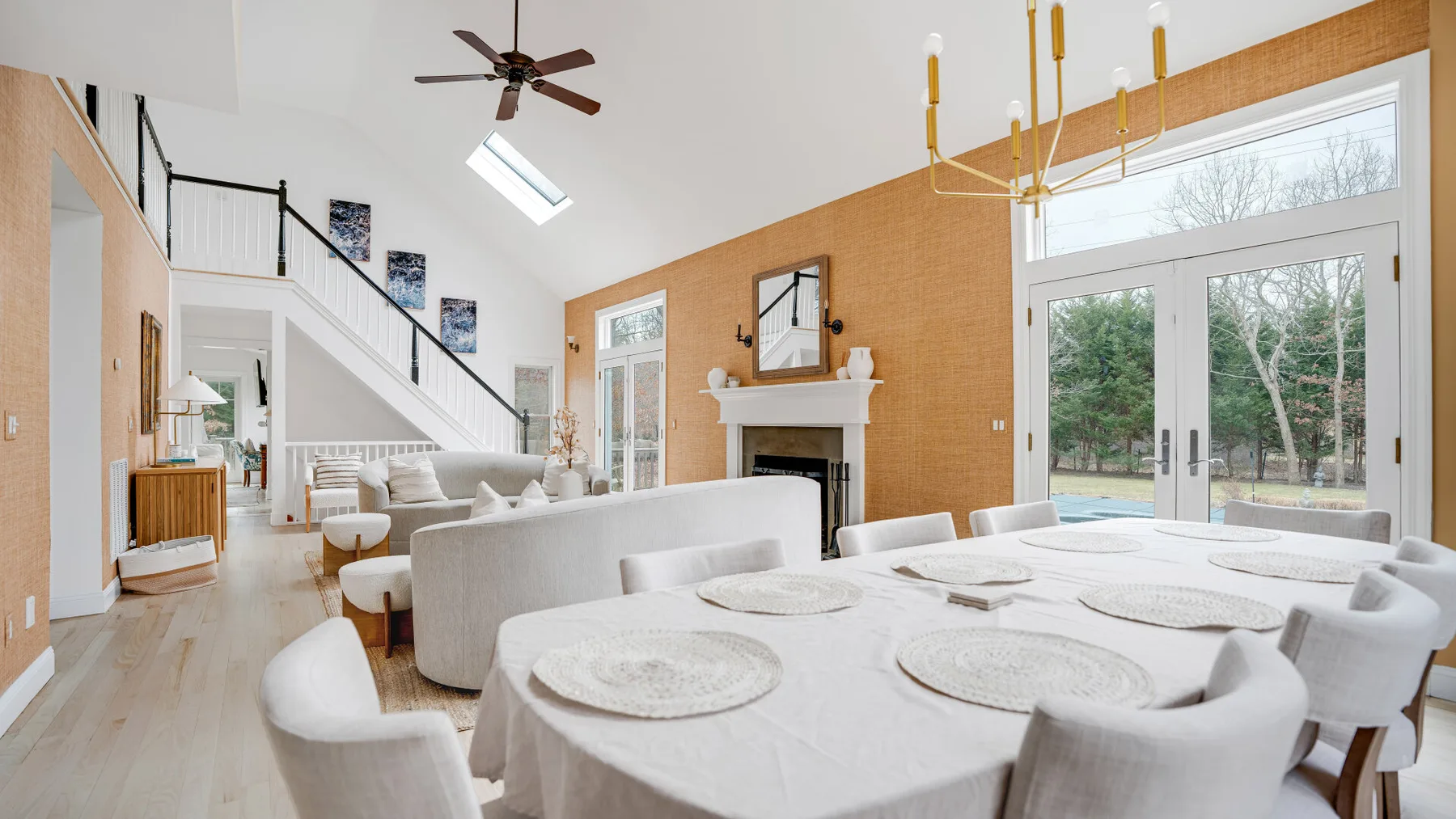 Un luminoso espacio diáfano de comedor y sala de estar, con una mesa grande junto a puertas acristaladas.