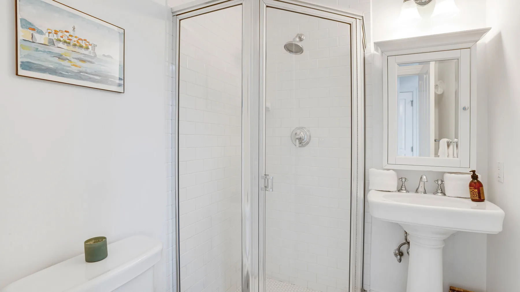Un baño luminoso con ducha y lavabo de pedestal.