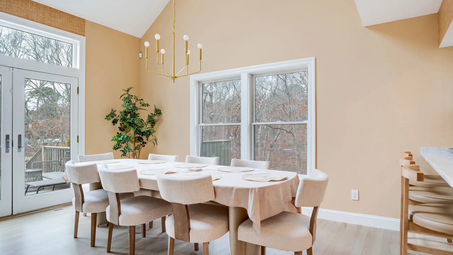 Un comedor luminoso con una mesa larga y asientos tapizados junto a grandes ventanas.