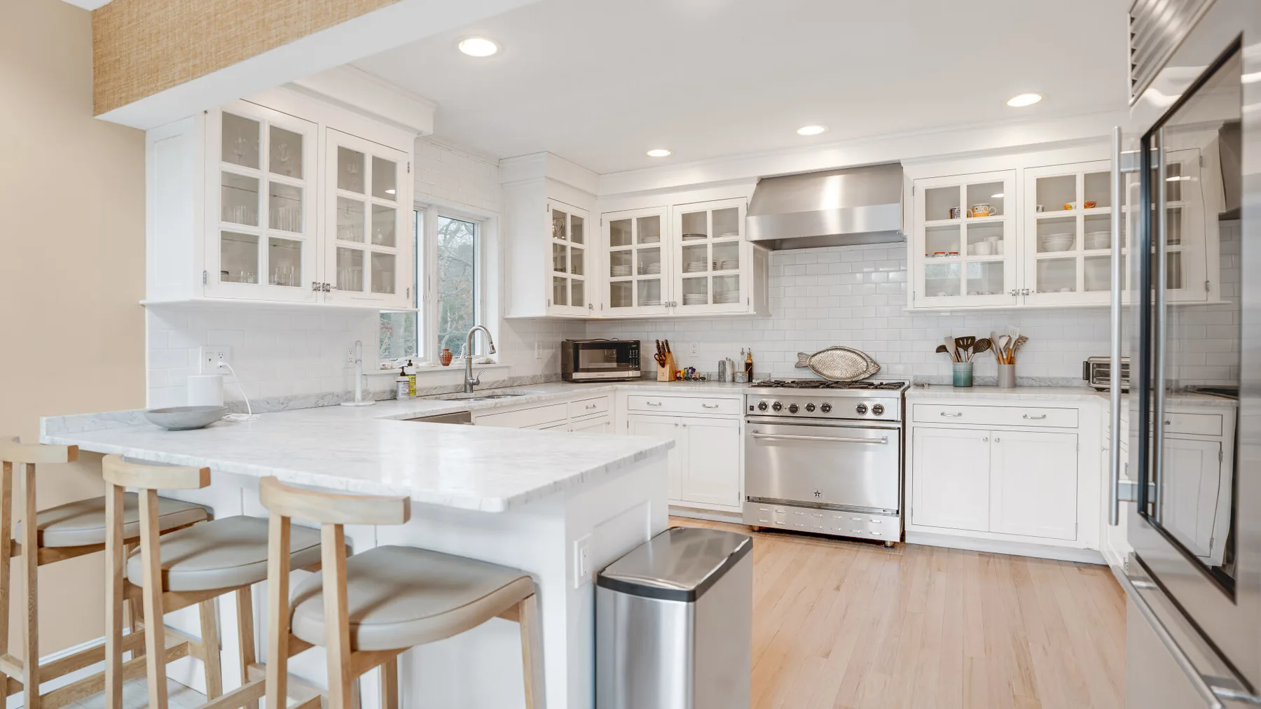Una cocina luminosa con gabinetes blancos, una estufa y una isla grande.