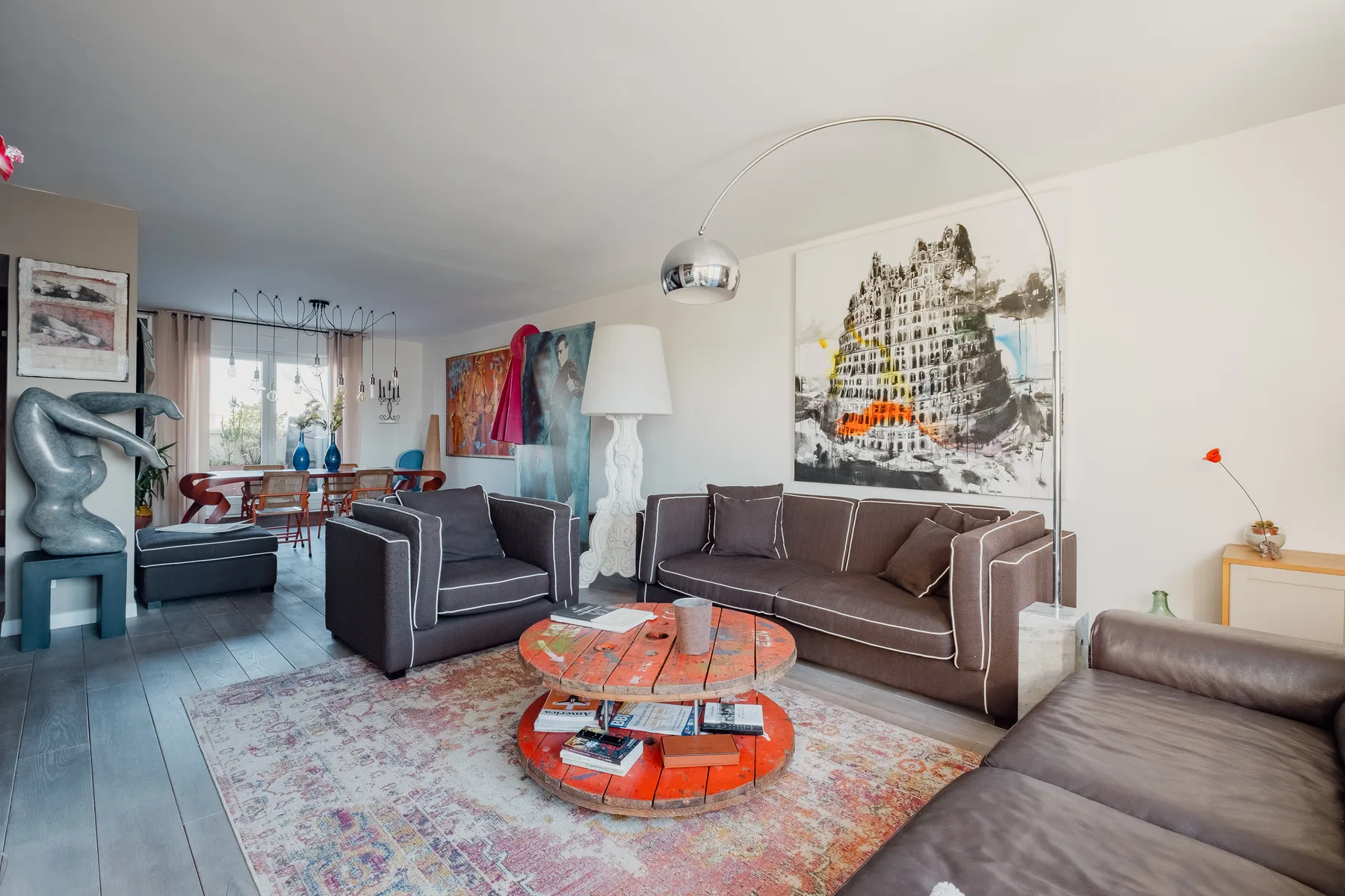 A living room with seating around a round coffee table and colorful wall art.