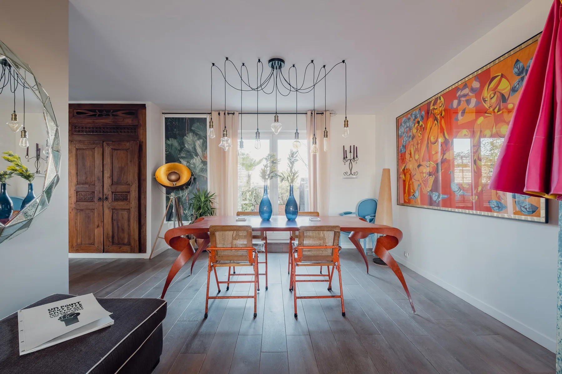 A bright dining room with a wooden table, chairs, and colorful wall art.